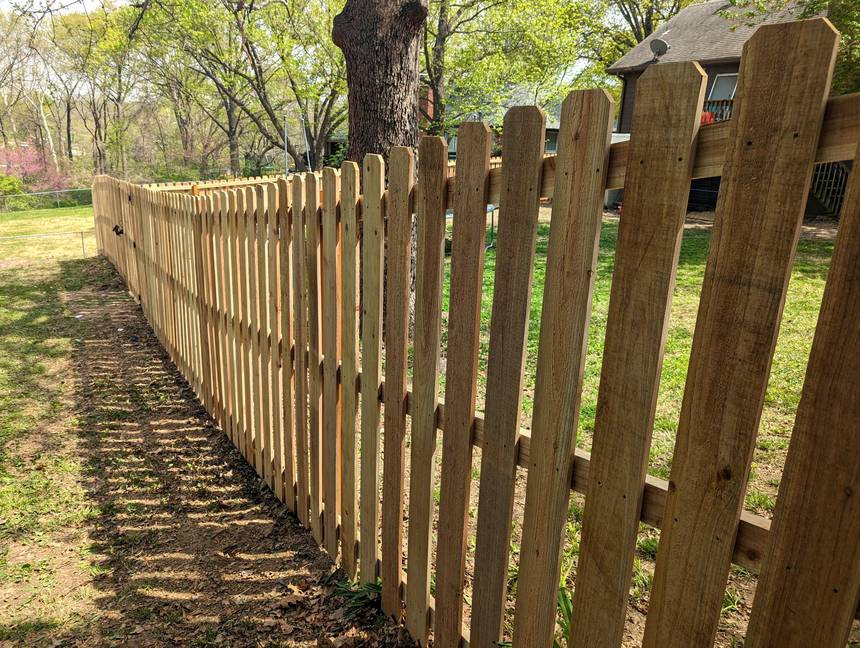 A shadowbox fence with cedar boards alternating on both faces of the rails, so the run looks the same from either yard.